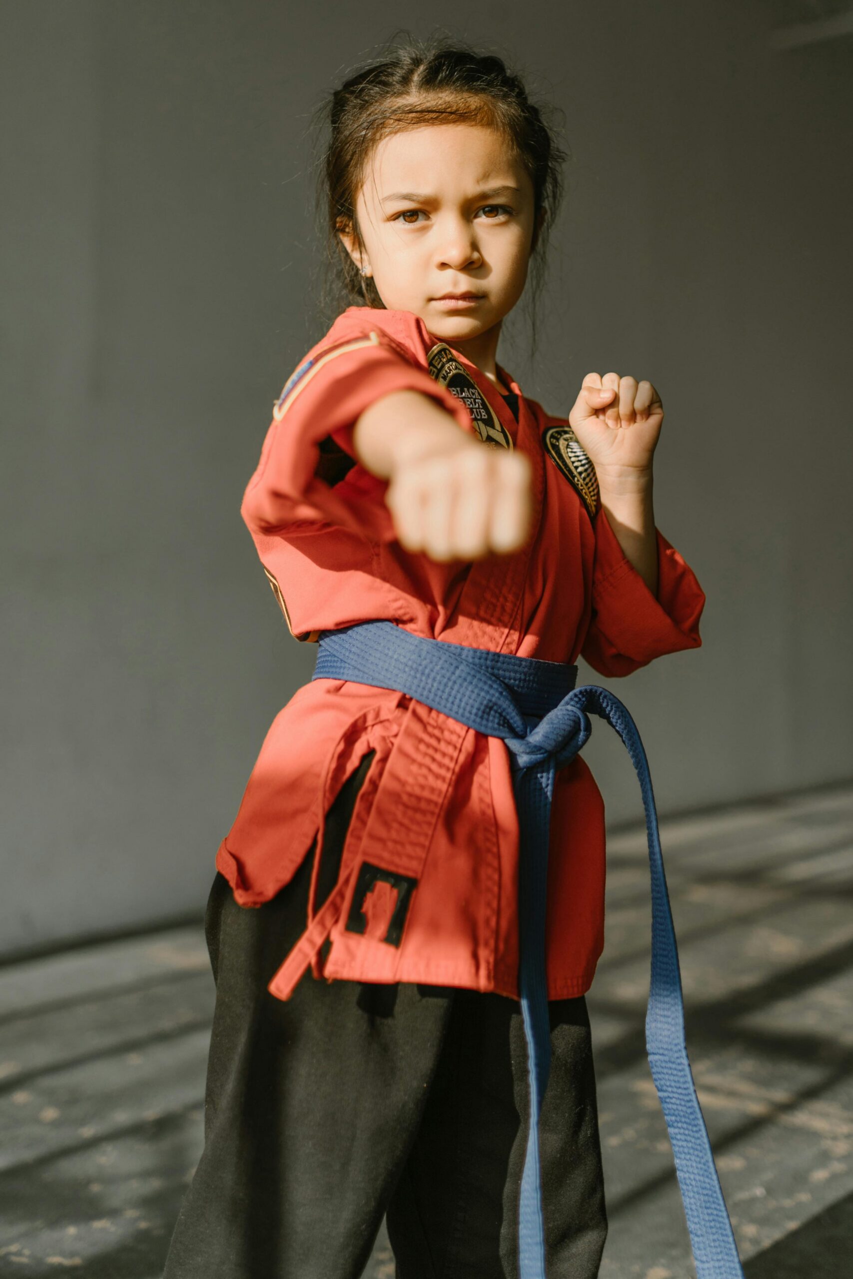 A determined young girl practicing martial arts in a brightly lit dojo.