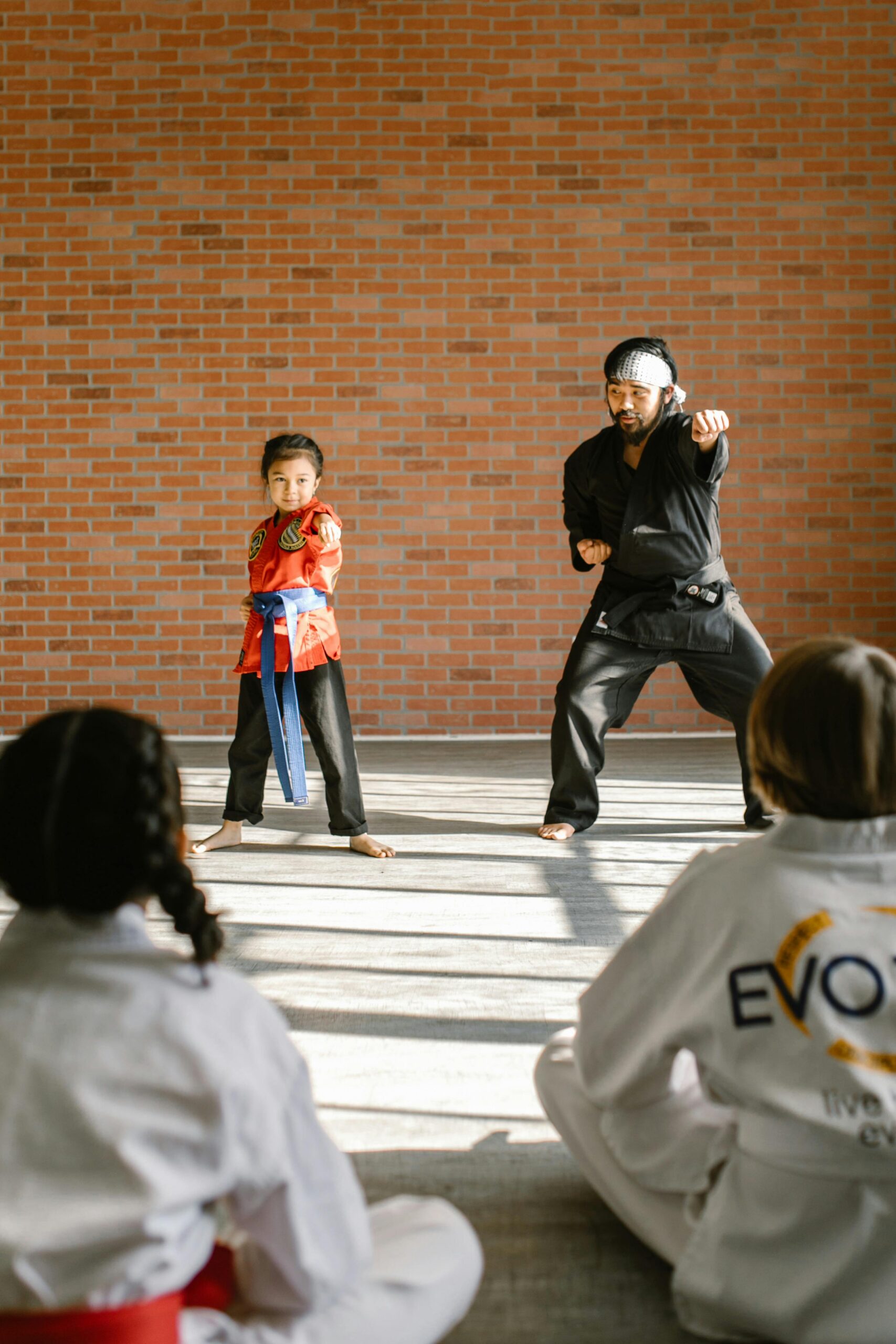 A karate instructor teaching a young student martial arts techniques in a dojo.